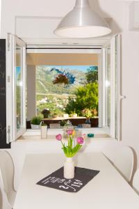 un jarrón con flores en una mesa frente a una ventana en Apartments Trio- An amazing view of Split en Klis