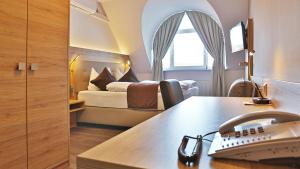 a hotel room with a bed and a desk with a telephone at Hotel Bauschheimer Hof in Rüsselsheim