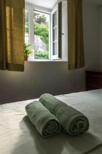 three rolled towels sitting on a bed with a window at Apartment Matijas in Trstenik