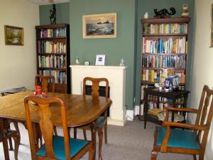 a dining room with a table and chairs and bookshelves at St Jude's Bed & Breakfast in Dersingham
