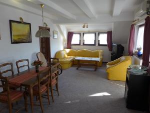 sala de estar con muebles de color amarillo, mesa y sillas en Lakeside Apartment, en Tihany