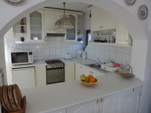 a white kitchen with a bowl of fruit on the counter at Lakeside Apartment in Tihany