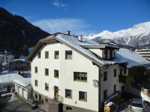 a white building with snowy mountains in the background at Appartements Klapeer in Nauders