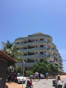 un edificio de apartamentos alto con gente parada frente a él en Condomínio Verdes Mares, en Arraial do Cabo