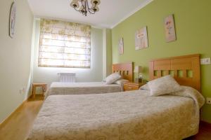 2 camas en una habitación con paredes verdes y ventana en Apartamento Sella y Mar - VUT12AS, en Ribadesella