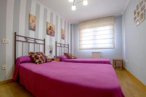 um quarto com 2 camas e cobertores roxos em Apartamento Sella y Mar - VUT12AS em Ribadesella