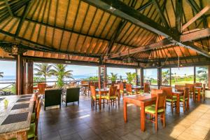 un restaurante con mesas y sillas y vistas al océano en Arton Resort & Beach Club, en Pulukan