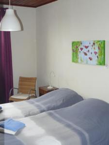 a bedroom with a bed and a chair and a painting at Auberge Fleurie in Saint-Nizier-sur-Arroux