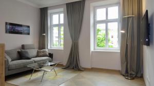 a living room with a couch and two windows at Sonnberg Design Apartment in Vienna