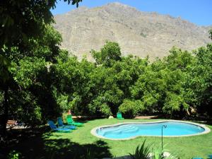 a swimming pool with chairs and a mountain in the background at Cabañas Nogalia in San Alfonso