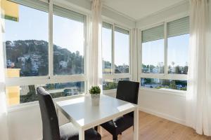 a white table and chairs in a room with windows at Estudio Playa Candado in Málaga