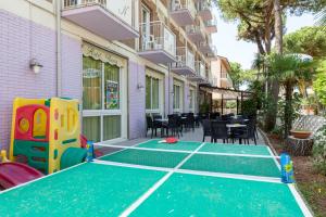 an outdoor ping pong court with tables and chairs at Hotel Nevia in Cervia