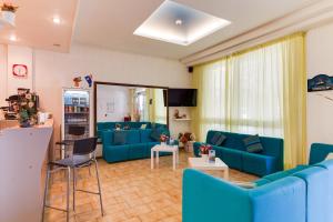 una sala de estar con sofás y sillas azules en Hotel Nevia, en Cervia