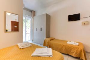 a hotel room with two beds and a mirror at Hotel Nevia in Cervia