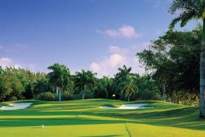 a green golf course with palm trees in the background at Family Complex beside Beach w/Pool Montego Bay #1 in Montego Bay