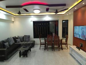 a living room with a couch and a table and a tv at Balani House in Navi Mumbai