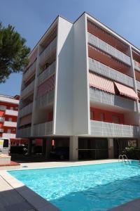 an apartment building with a swimming pool in front of it at Gabbiano - Appartamenti in Bibione +16 photos