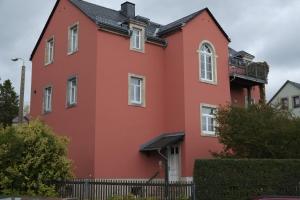 ein rotes Haus mit einem schwarzen Zaun in der Unterkunft Gästewohnung Elström in Dresden