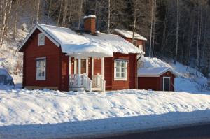 Une petite maison rouge avec de la neige au sol dans l'établissement Lilla Huset, à Stöllet