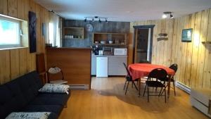 a living room with a couch and a table and a kitchen at Le Saint Alex in Saint-Alexis-des-Monts