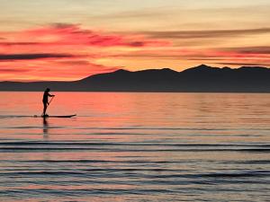 a man on a paddle board in the water at sunset at Troon Beachcombers in Troon