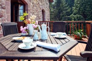 a wooden table with cups and saucers on a patio at Jardin de Carrejo in Cabezón de la Sal