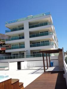 un edificio blanco con una terraza de madera delante de él en Condomínio Beach Town., en Arraial do Cabo