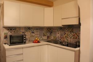 a kitchen with white cabinets and a microwave at Casetta di Arcangelo in Cisternino
