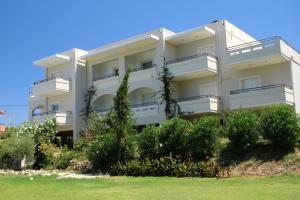 een wit appartementencomplex met balkons en struiken bij Merabello Apartments in Agia Marina Nea Kydonias