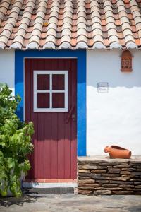 czerwone drzwi na domu z dachem kaflowym w obiekcie Monte dos Parvos w mieście Vila Nova de Milfontes