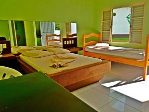 a group of beds in a room with green walls at Hotel Comodoro De Quaraí in Quaraí