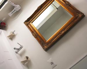 a mirror with a wooden frame on a bathroom wall at Duomo Luxury Suite Catania in Catania