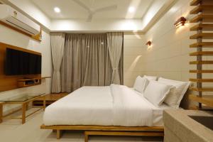 1 dormitorio con 1 cama blanca y TV en Hotel 440, A Serene Stay, en Ahmedabad