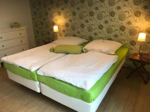 エッカーンフェルデにあるSEASIDE APARTMENTS - DREAMY GREENのベッドルームのベッド(緑と白のシーツ付)