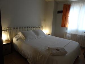1 dormitorio con cama blanca y ventana en Can Seuba, en Rellinars