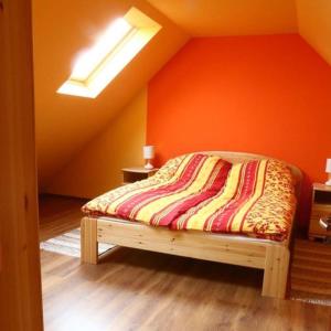 Bett in einem Zimmer mit orangefarbener Wand in der Unterkunft Tiszavirág Vendégház in Tiszabábolna