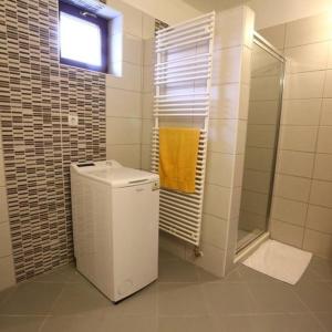a bathroom with a toilet and a shower with a yellow towel at Tiszavirág Vendégház in Tiszabábolna