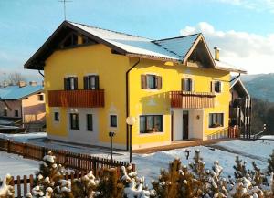 a yellow house with a fence in the snow at Casa Gialla in Lavarone