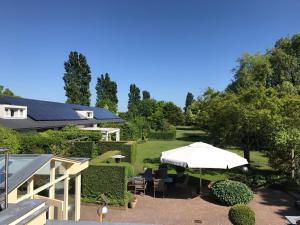 een patio met een parasol en tafels en stoelen bij Borneman Buitenhof - Privé Appartement in Houten