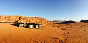 a desert with three buildings in the sand at Wadi Rum Starlight Camp in Wadi Rum