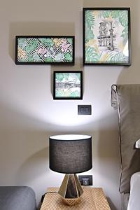 una lampada su un tavolo in un soggiorno con due quadri di Gemini Suite a Salerno