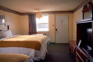 a hotel room with two beds and a flat screen tv at South Wind Inn in Liberal