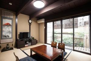 a living room with a wooden table and a tv at Maeniiya Machiya Inn in Kyoto