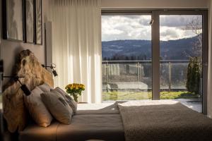 a bedroom with a bed and a large window at ApartWisła in Wisła