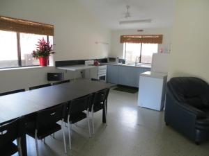 cocina con mesa, sillas y nevera en Fraser Forever Orchid Beach Fraser Island en Fraser Island