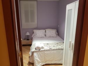 a small bedroom with a bed with white sheets and pillows at Pradera de San Isidro in Madrid