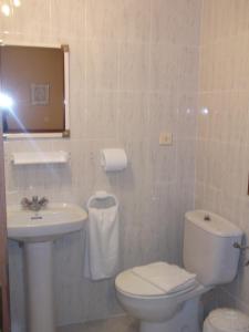 a bathroom with a white toilet and a sink at Pensión Rada in Solares