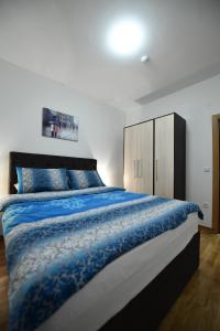 een slaapkamer met een groot bed met een blauw dekbed bij Dvori Apartments in Kopaonik