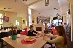twee kinderen aan een tafel in een restaurant bij Dvori Apartments in Kopaonik