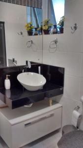 a bathroom with a white sink and a mirror at Apartamento Feliz in Aracaju